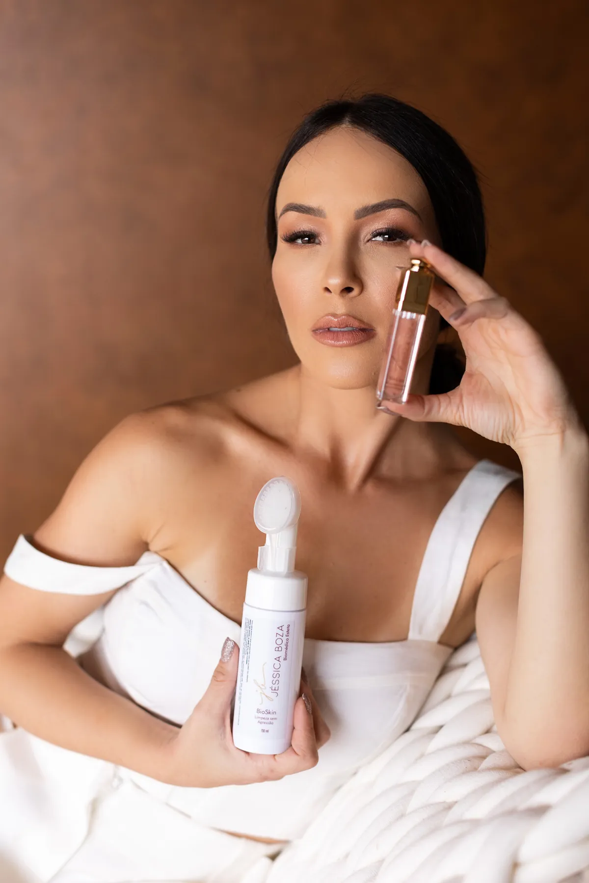 Jessica Boza, biomédica esteta em Curitiba, segurando os dermocosméticos da sua linha de skincare